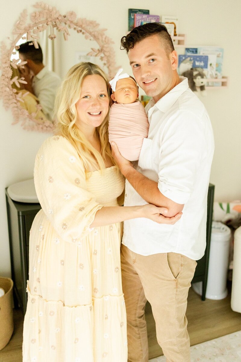 Parents smiling and holding up their newborn baby, taken by minneapolis newborn photographer Kacey Wyrick