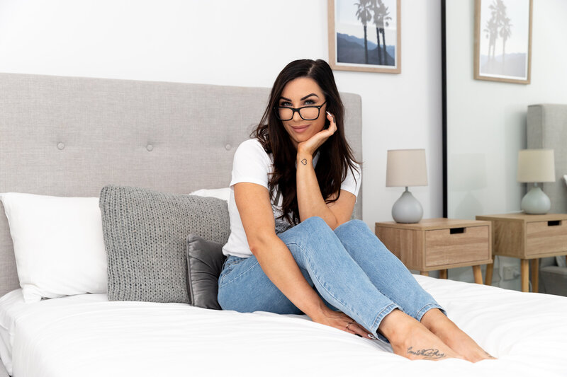 Woman sitting on a bed in jeans