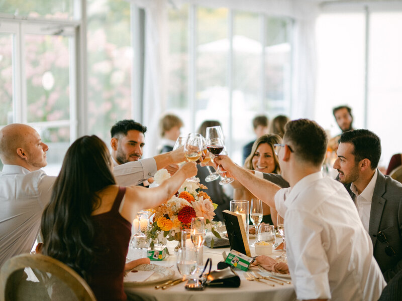 Wedding guests celebrating and cheers their glasses at Harding Waterfront Estate in Toronto