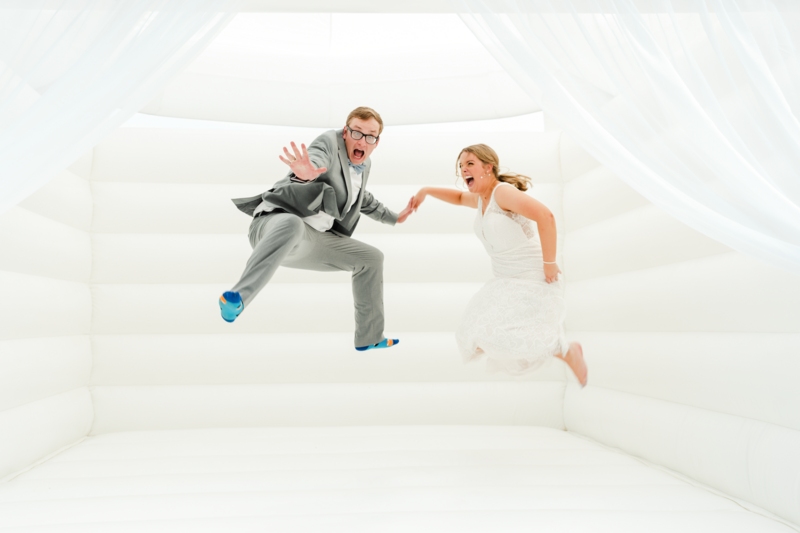 Bride and Groom jumping inside of a white bounce house