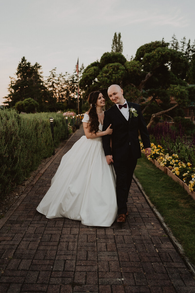 A wedding couple holding hands and standing in front of a massive log.