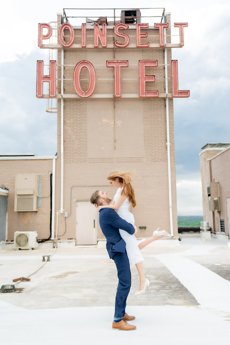 Greenville bride and groom outside Poinsett Hotel. The groom in a blue suit holding his bride wearing a short white dress with white heels.