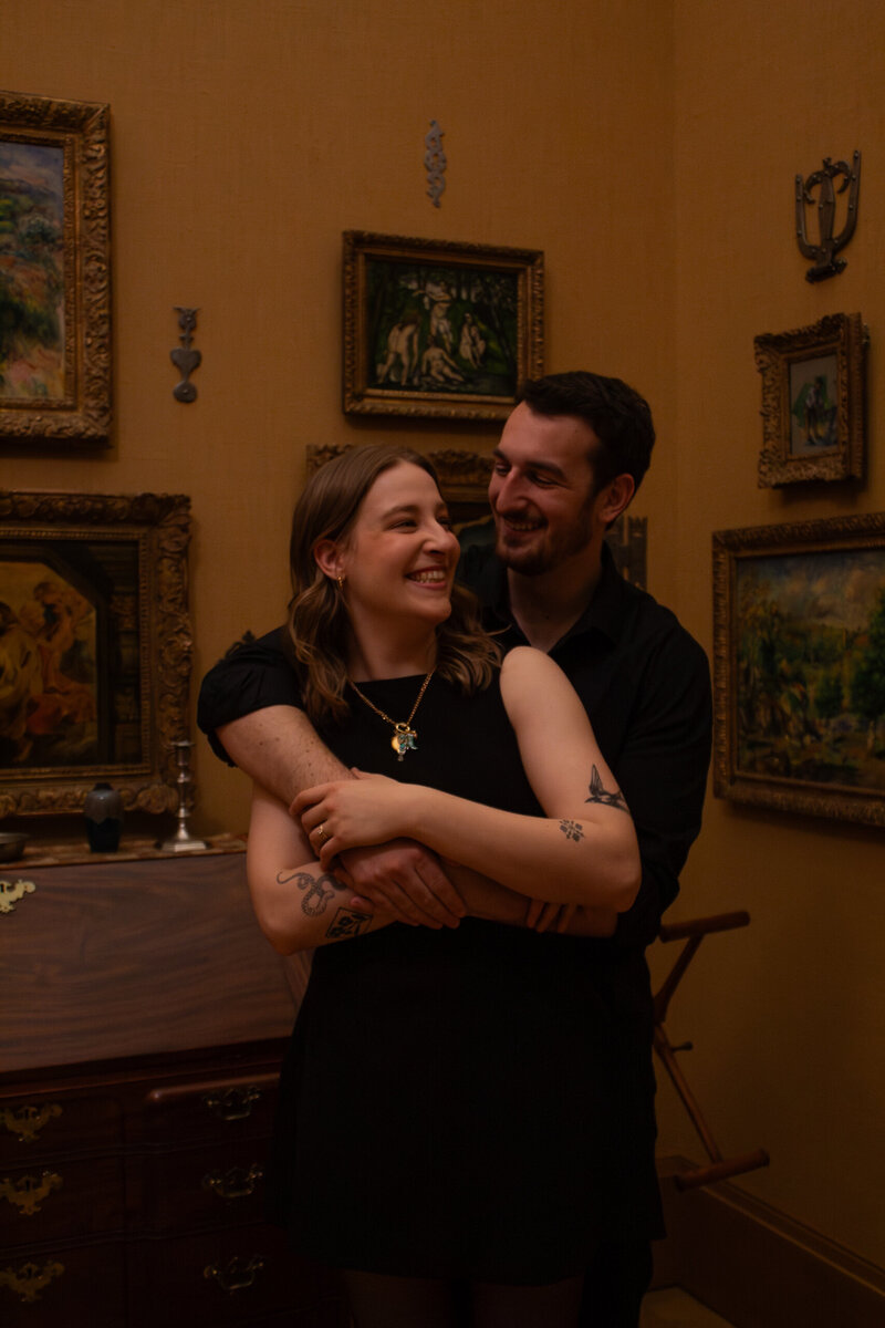 A couple embracing inside of the Barnes Foundation in Philadelphia, Pennsylvania. It is an engagement session at an art museum.