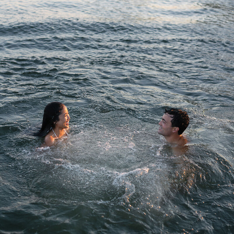 A woman and a man are swimming in a large body of water