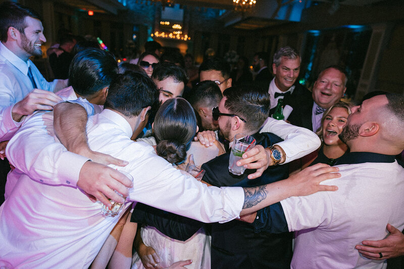 Bridal party share a group hug on the dance floor during the wedding reception.