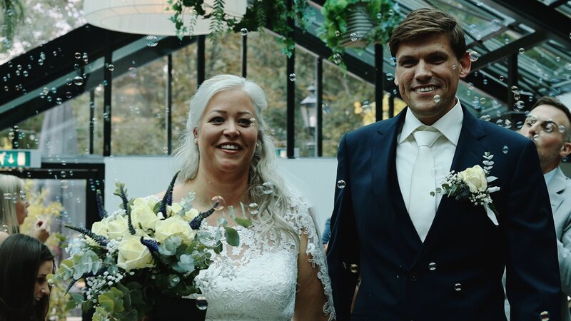 Ceremonie met bellenblaas. Bruidspaar loopt de ceremonie uit met trouwvideograaf Sterly