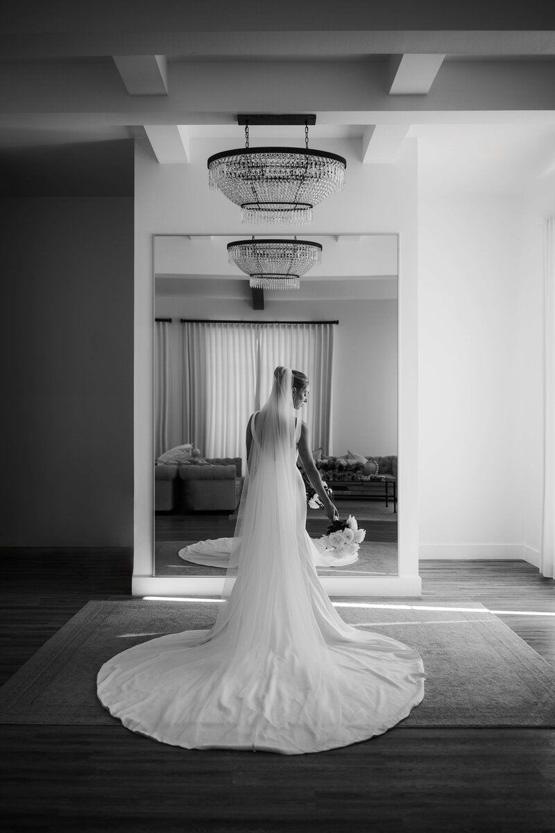 Black and white image of bride looking back over her shoulder holding her bridal bouquet