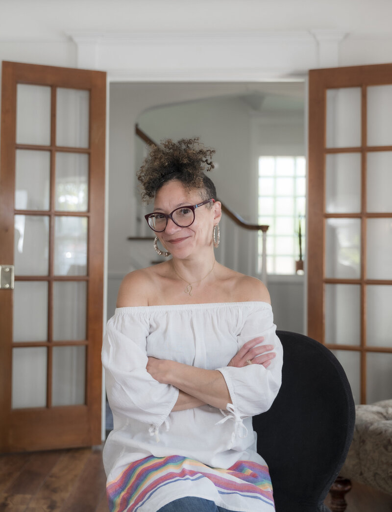 An image of a woman sitting down smiling and wearing glasses