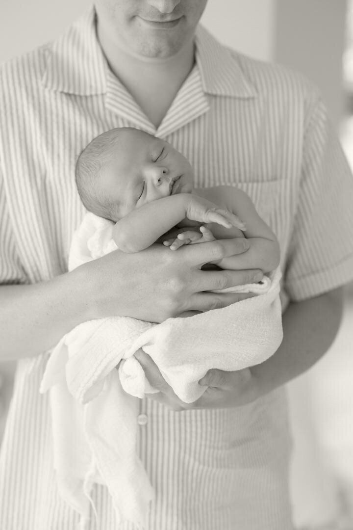 cute baby in dad's arms at a newborn photo session in Iowa City