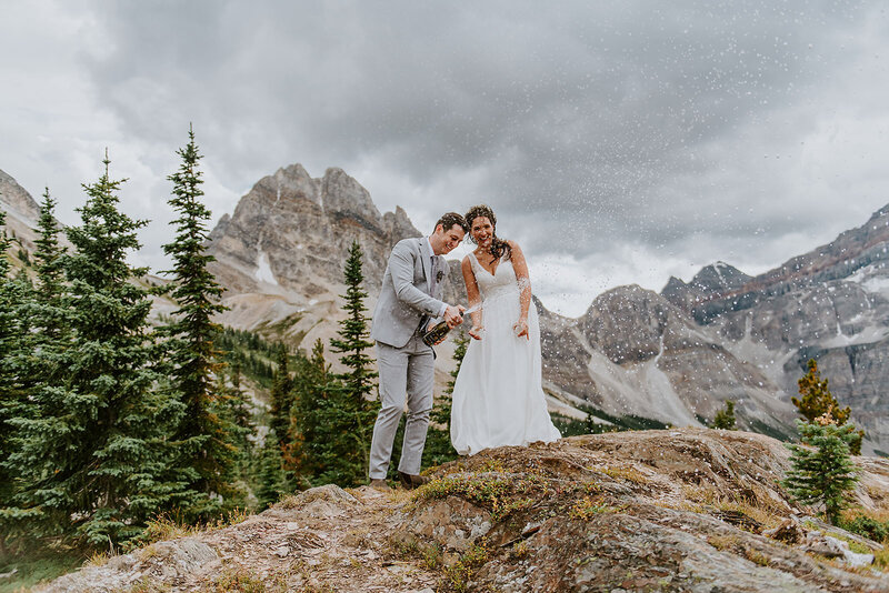 Bride and Groom in front beautiful Chatterbox Falls in British Columbia Canada at their romantic elopement. Couple sharing first kiss in the mist from the majestic waterfall.