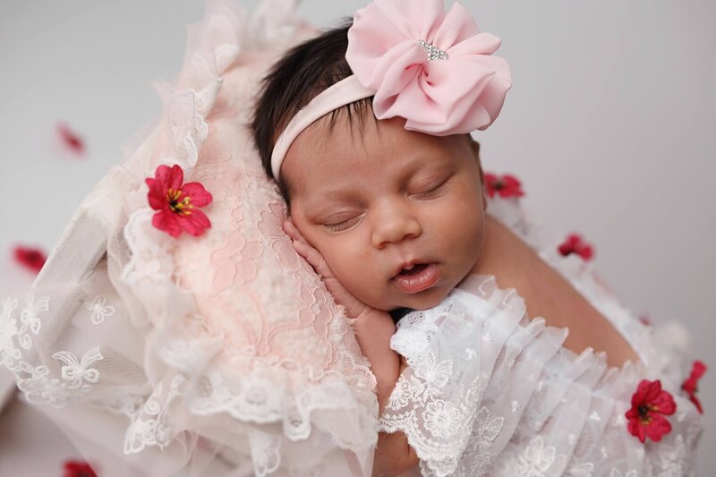 Newborn posing on small brown chair in brown overalls.