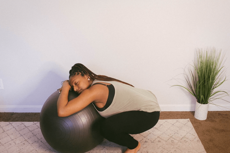 pregnant woman squatting and using exercise ball for support