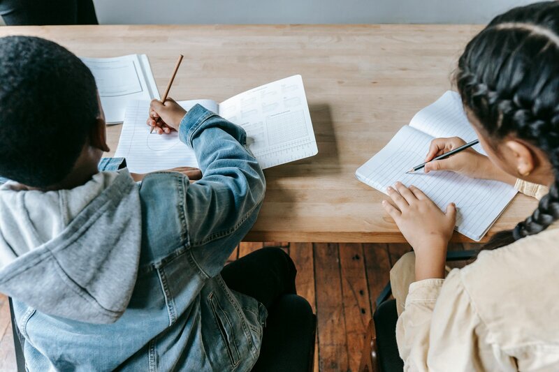 girl and boy sitting at desk writing in notebooks