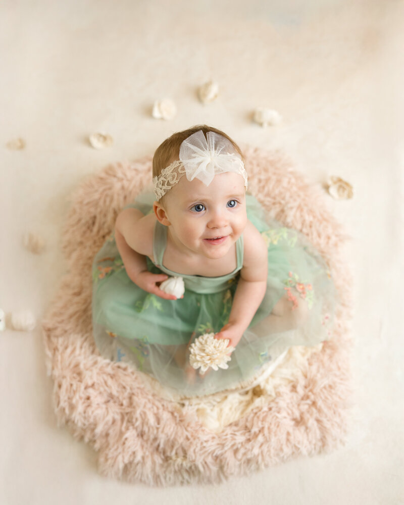 A toddler smiling for milestone pictures in Midland Michigan. 