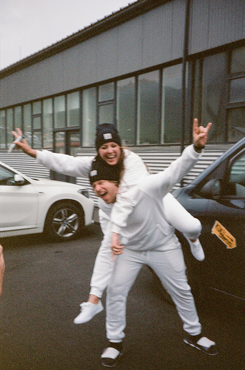 Film photo of groom giving piggy back to bride in sweats celebrating Iceland Elopement