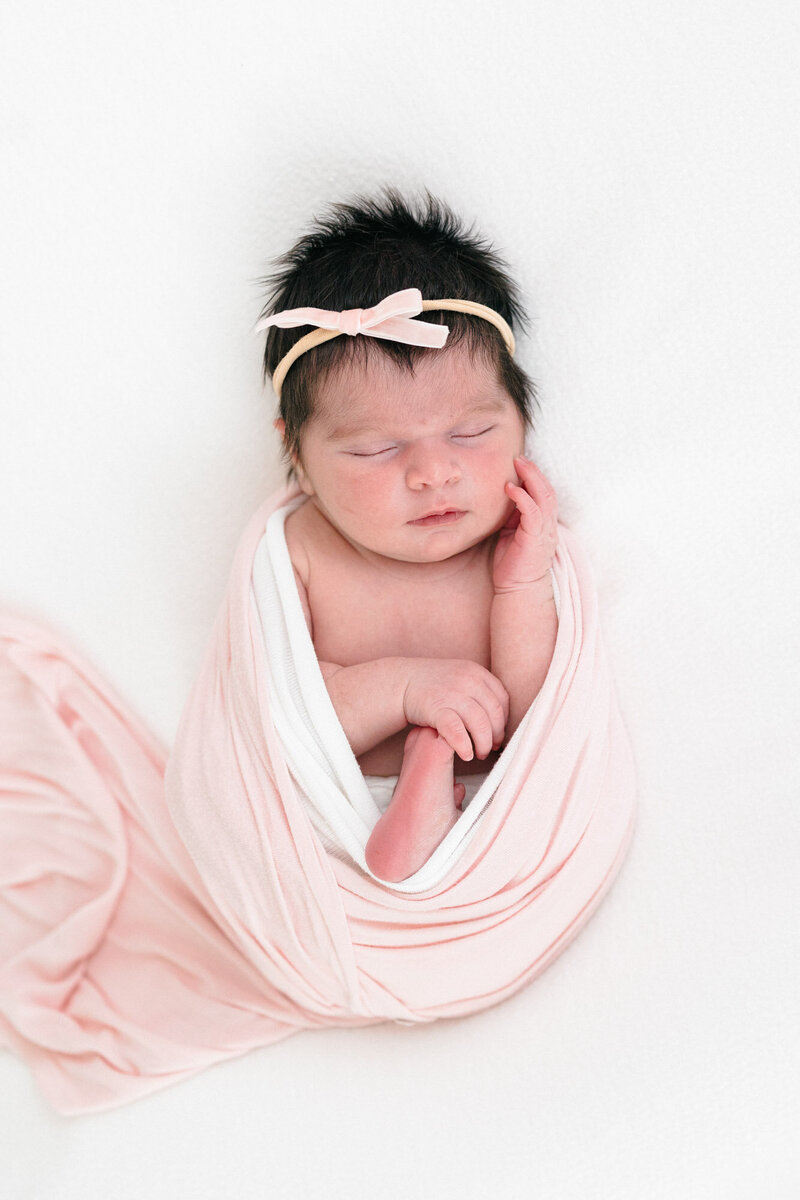 Newborn baby girl wrapped in a pink swaddle during her northern kentucky newborn photography session