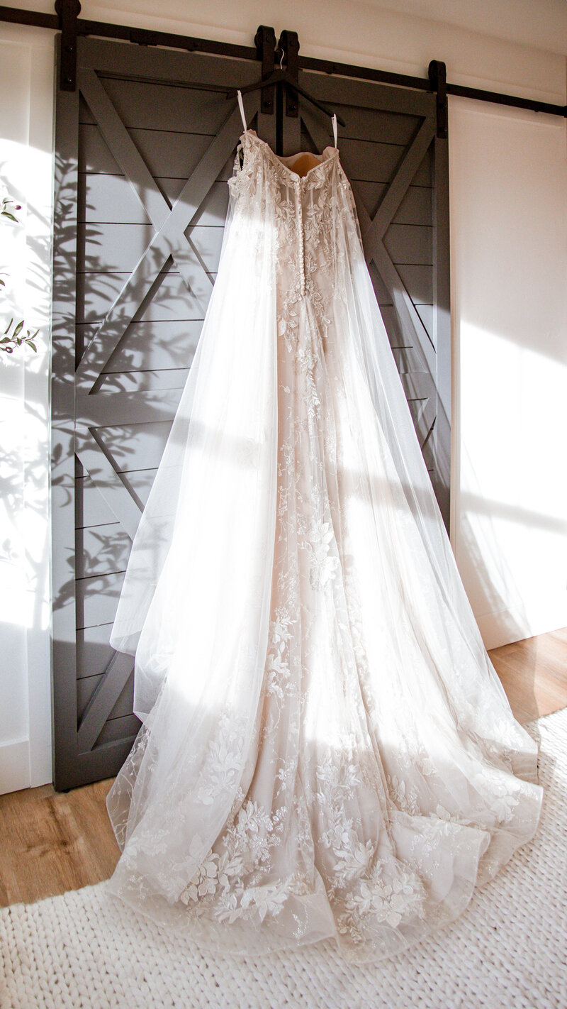 Wedding dress handing from the black barn doors with sunbeams shooting across it. In the bridal suite, of course.