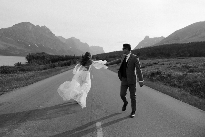 bride and groom posing in the desert in front of a car