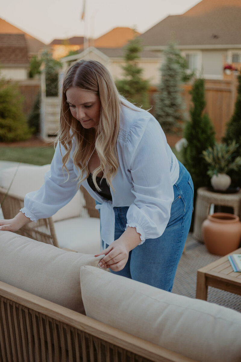 designer fluffing pillows on the outdoor sofa