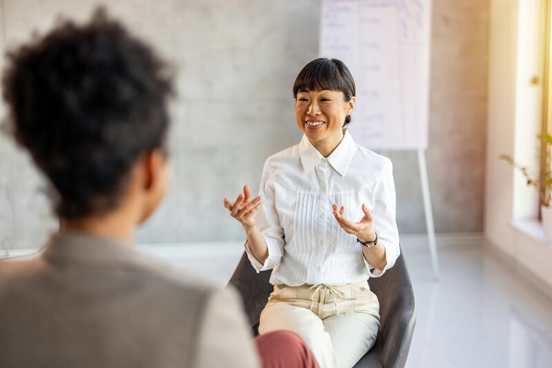asian woman sitting in a chair across from another woman