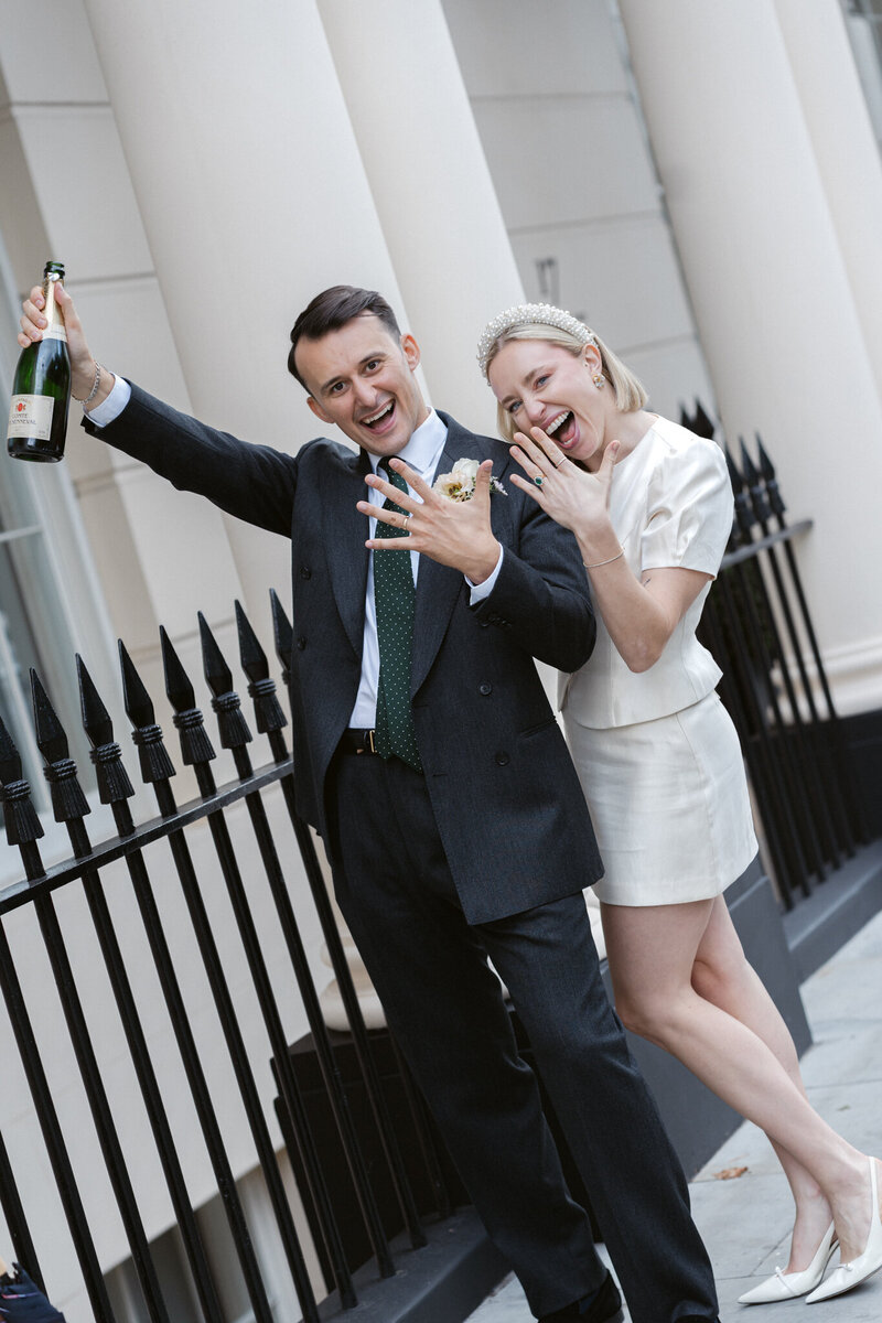 Portrait of a bride sitting on a grooms lap with cocktails after getting married in London city