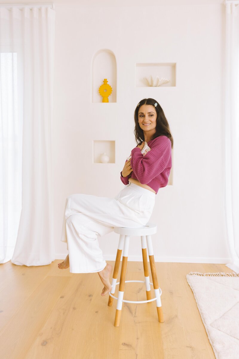 marisa sits on stool holding website copywriting course