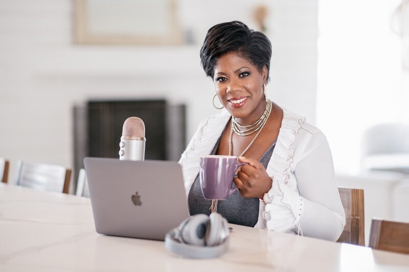 wedding planner sitting with a cup of coffee next to a laptop and microphone