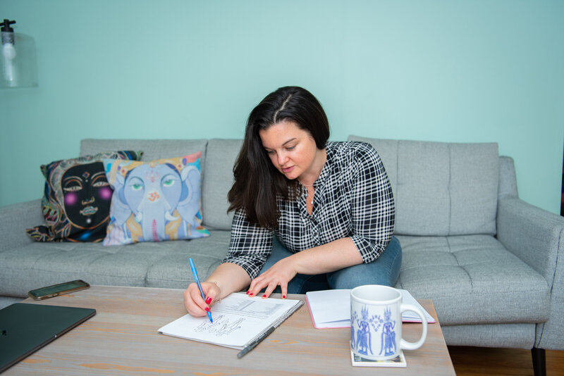 A woman sitting and writing on a worksheet at the coffee table.