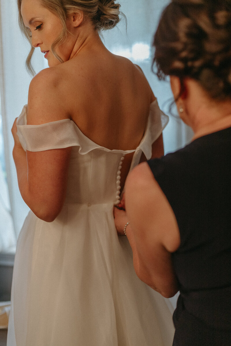 Brides mother helps button wedding dress in Ottawa Ontario