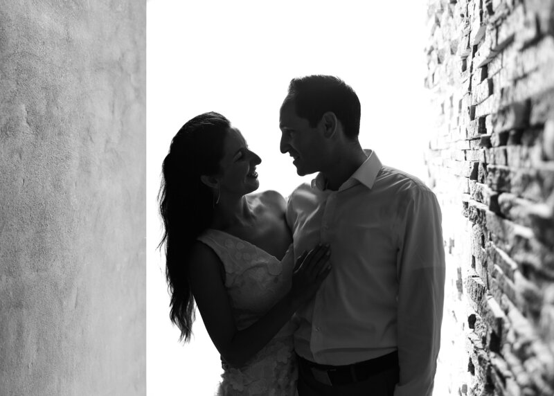 Couple poses, backlit, looking at each other.