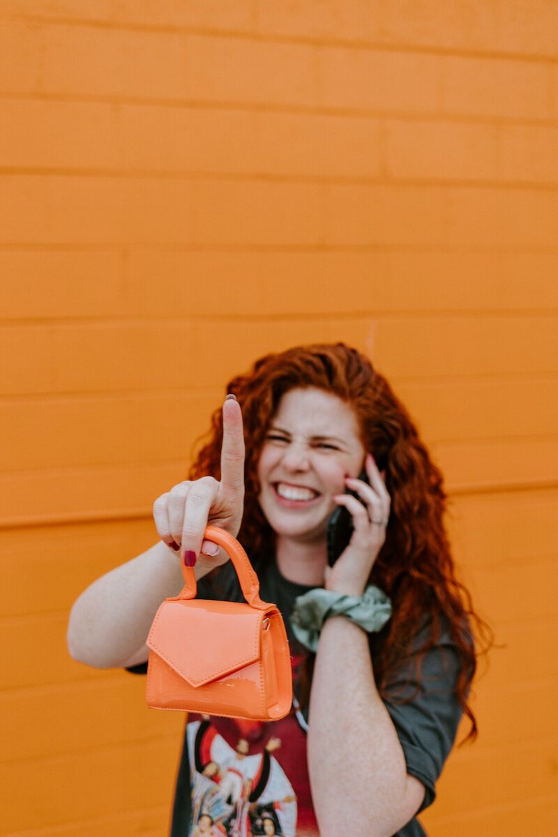 Leanna holds a bright orange purse.