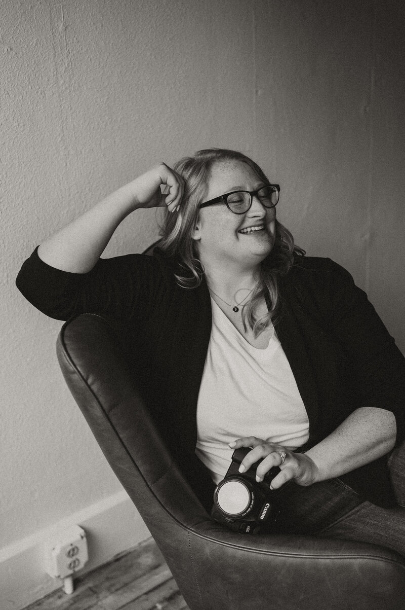 Black and white image of women smiling, wearing glasses dressed professionally. 