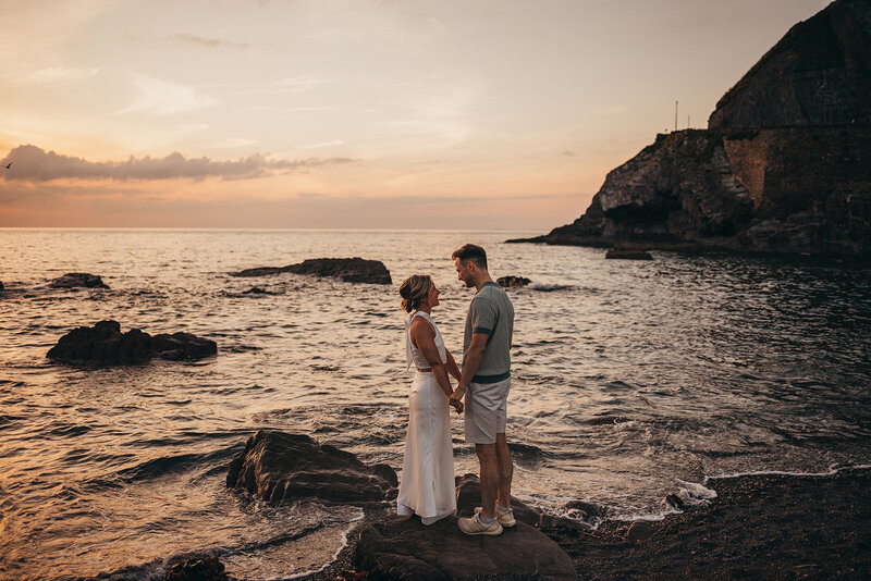 couple hold hands by a tranquil ocean