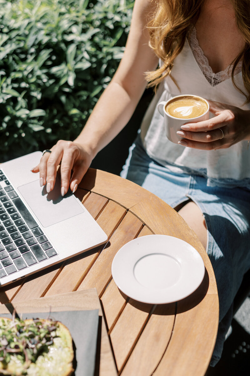 Top view of open laptop and empty notebook with plant, essential oils, and cozy workspace vibe