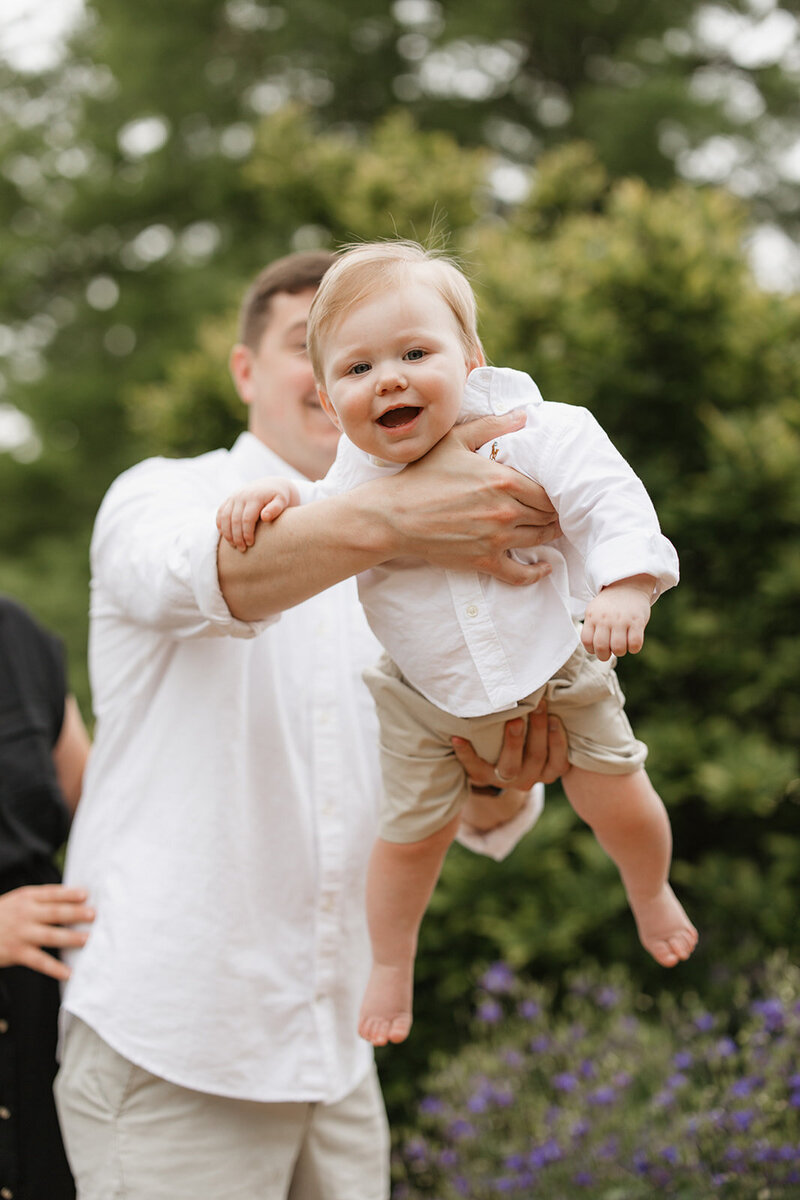 Dad holding 1 year old son up with him smiling at Missouri Botanical Garden