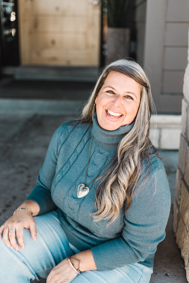 woman smiling and sitting on a front porch