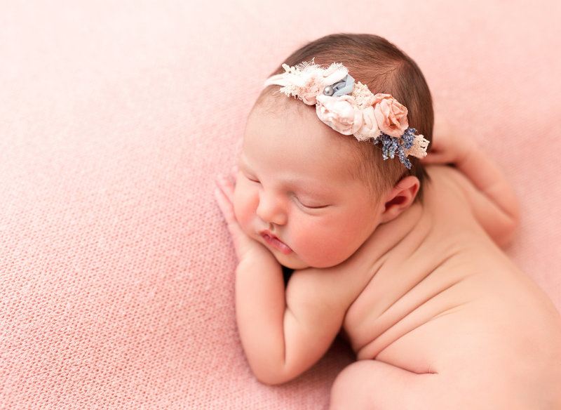 Newborn bay girl on pink blanket with headband