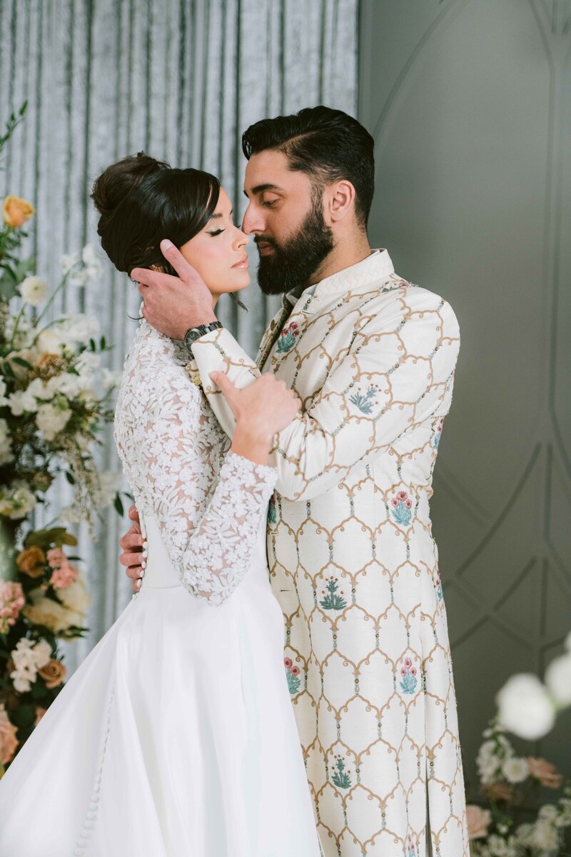 sikh couple wearing black and orange looking into each others eyes smiling
