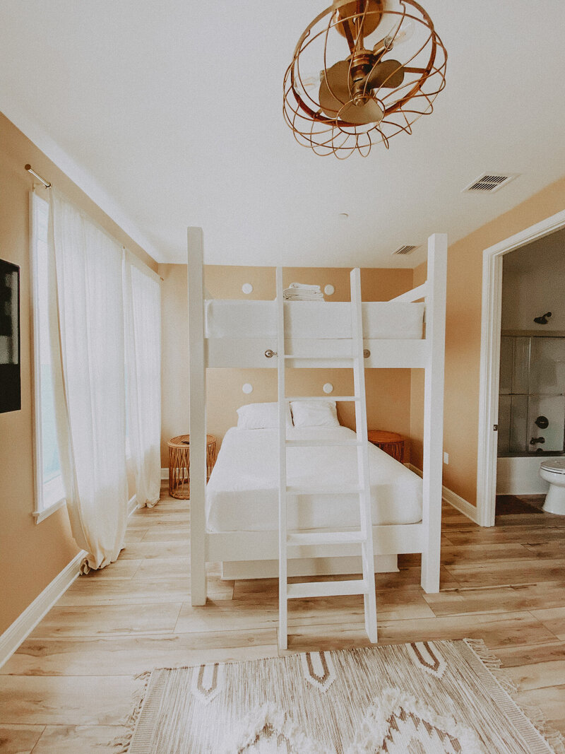 bedroom with white bunk bed and gold fan