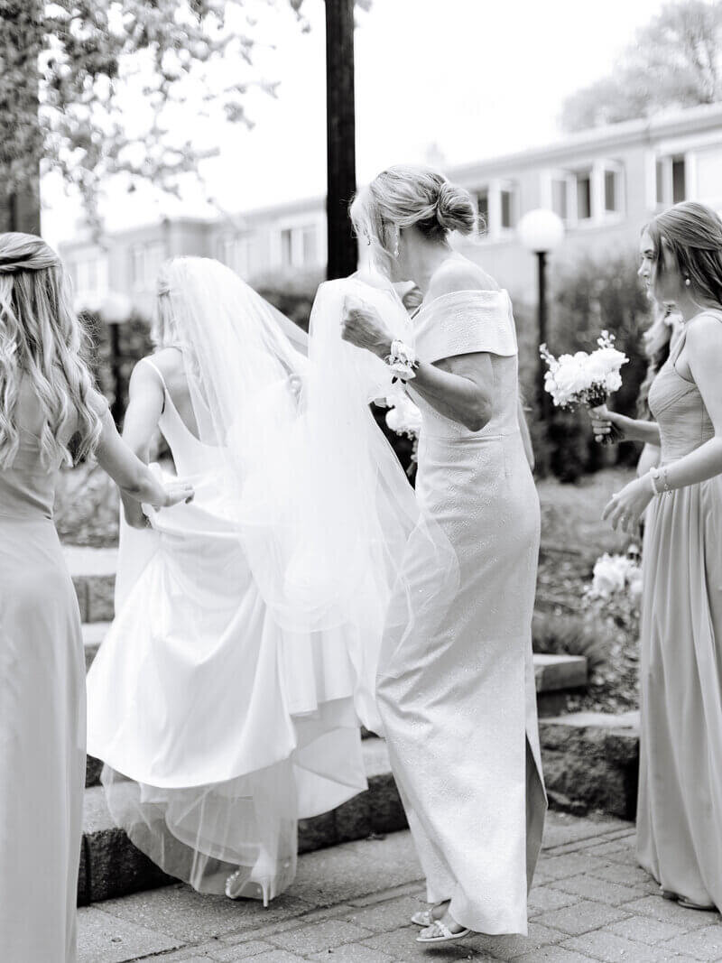 bride walking with mother of bride holding dress to show design by wedding planner minneapolis mn