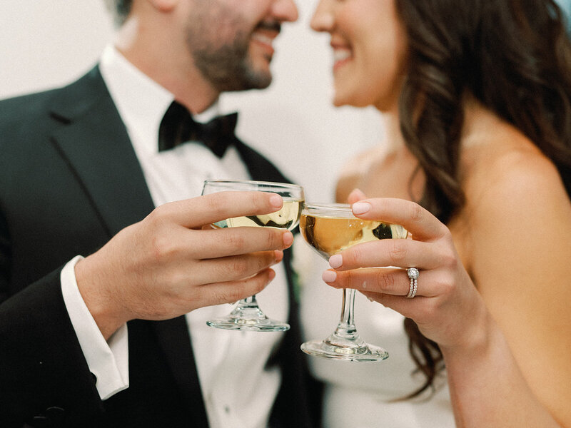 Bride and groom kissing with their reception and guests in the background