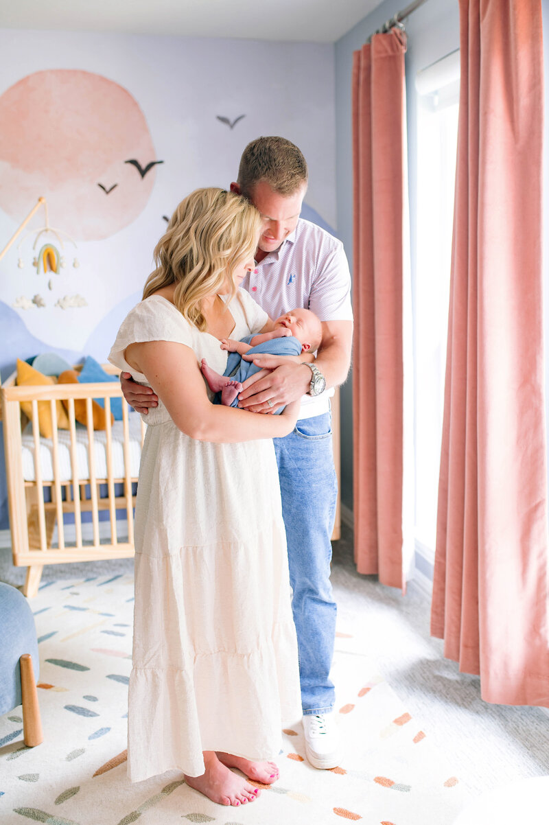 Parents holding their newborn baby during an in-home lifestyle session in Allen, Texas, photographed by Jennifer L. Kirk Photography. A tender, light-filled moment celebrating new life and family connection.