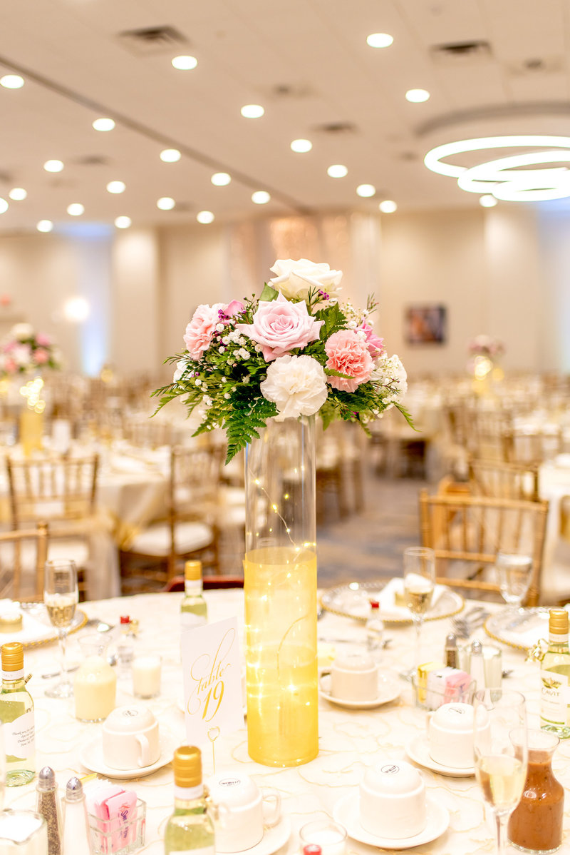 Reception room with gold details and white and pink floral centerpieces