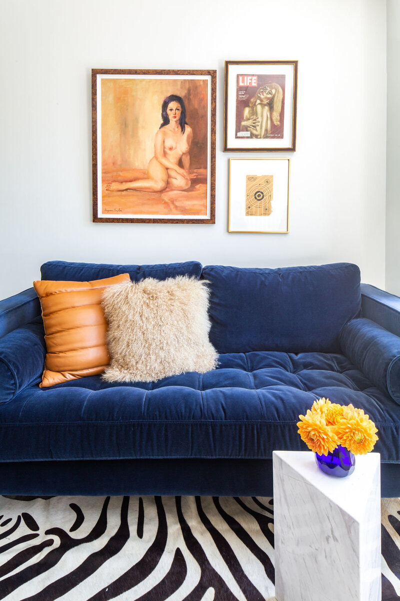 Masculine James Bond office space with navy velvet sofa, zebra cowhide rug and 1970’s nude oil painting.