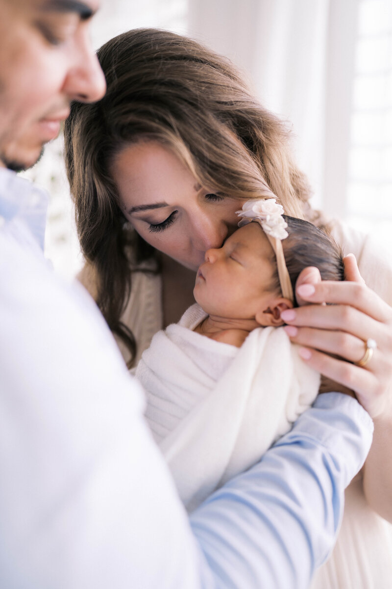 Newborn Portrait taken in a studio in Jacksonville with the mother in a creamy long dress while the baby snuggles on her shoulder