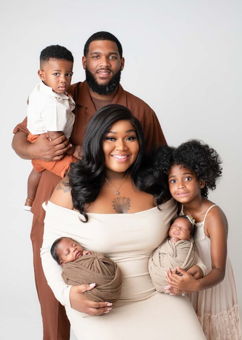 Newborn Photographer Birmingham, AL: Family with siblings holding 2 new babies in a professional studio.