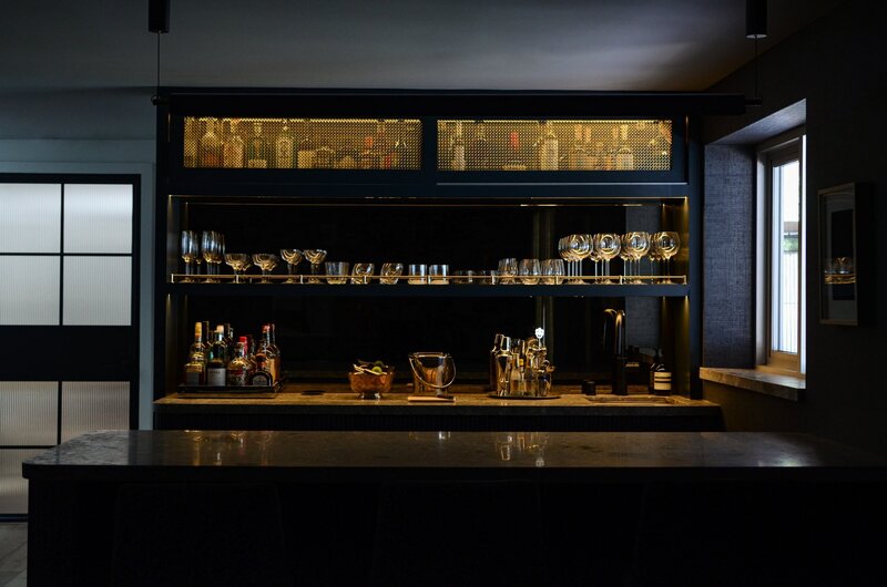 dark moody basement wet bar interior design Los Angeles custom built ins bespoke mood lighting fine art liquor bar display mirrored backsplash minimal ambient design ideas plans mini bar