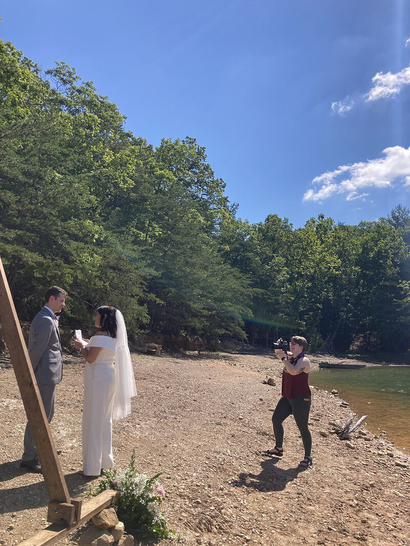 A couple reads their vows on the shores of Carvin's Cove in Roanoke, Virginia while their elopement photographer documents their ceremony on the sidelines.