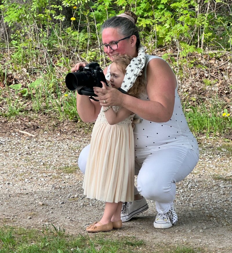 Denise shares the camera with a little one during a behind-the-scenes moment at a Paris, Ontario outdoor family session.