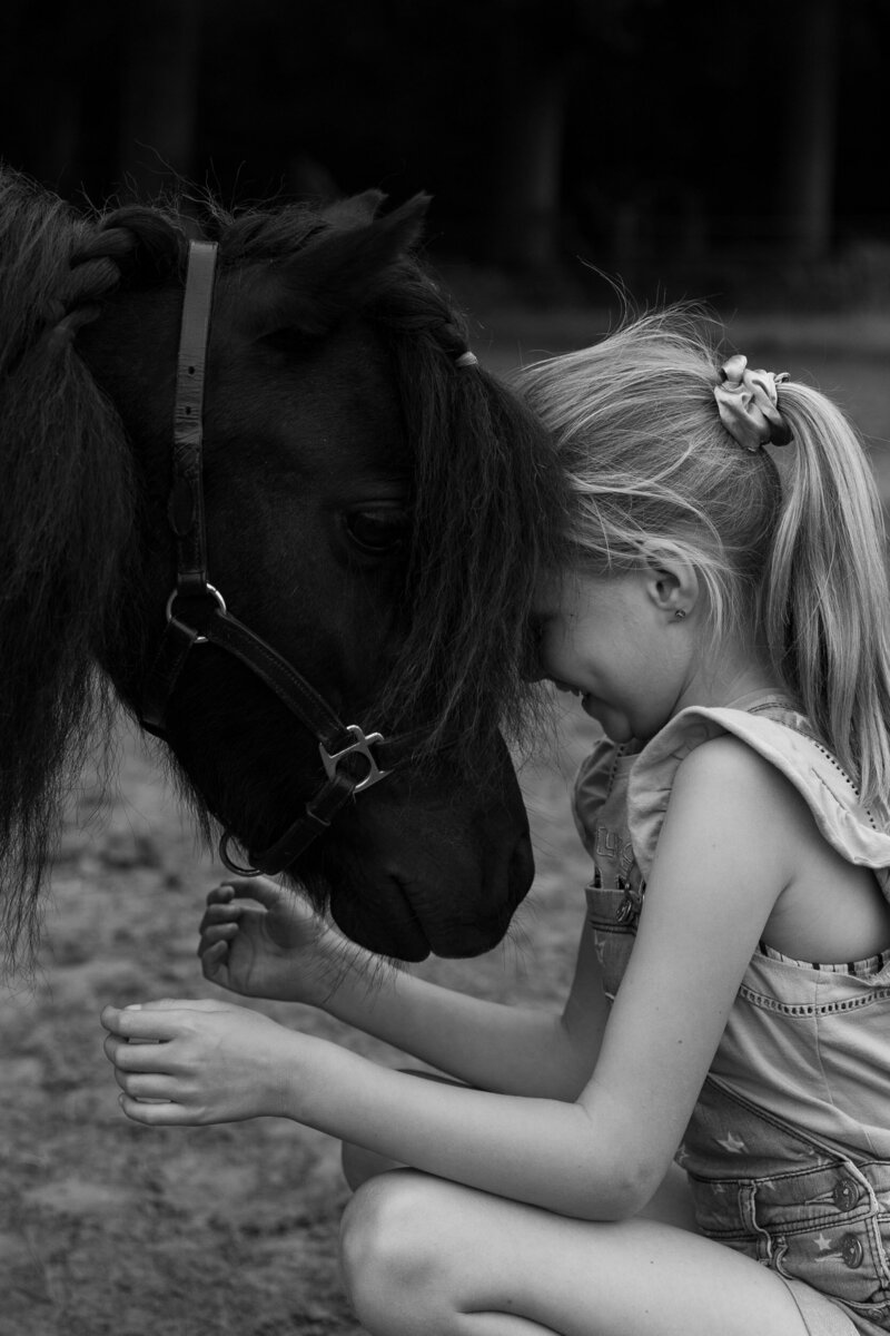Stralend kind samen met mini Shetland pony tijdens coaching met paarden  in Drenthe.